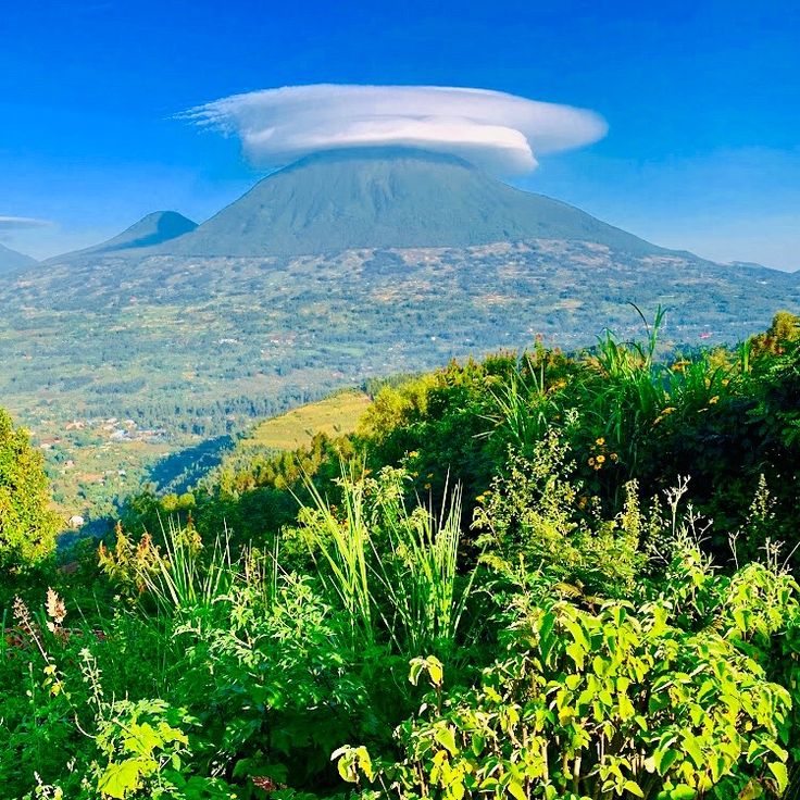 The snow capped peak of Mount Karisimbi in Rwanda topped with a unique white lenticular saucer cloud by excellent african safaris.