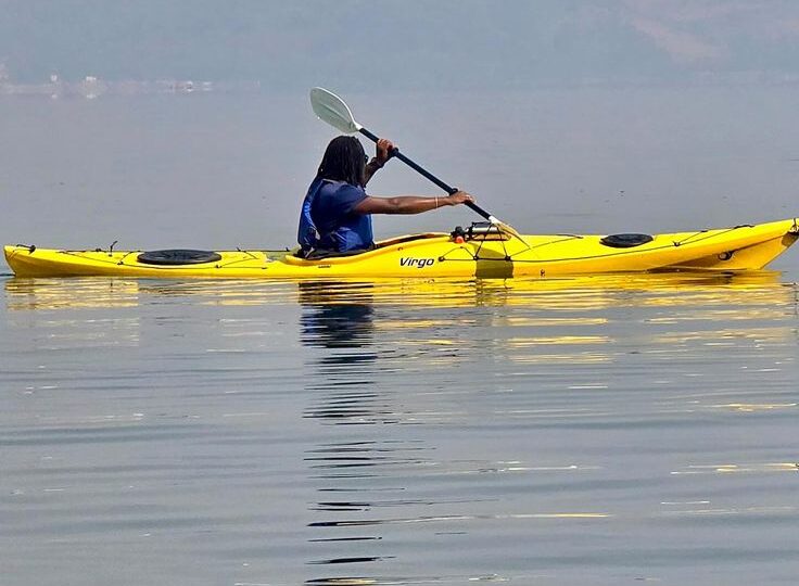 A traveler in a yellow sea kayak paddling on the calm, misty waters of Lake Kivu in Rwanda, near Rubavu (Gisenyi) by excellent african safaris.